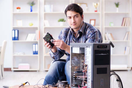 Disabled man on wheelchair repairing computer