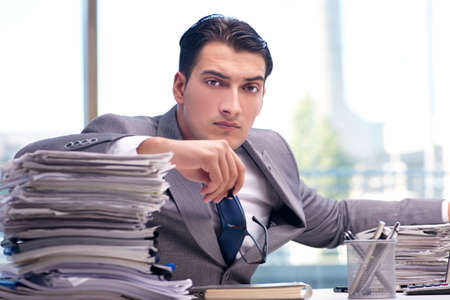 Busy angry businessman with heaps of paperの写真素材