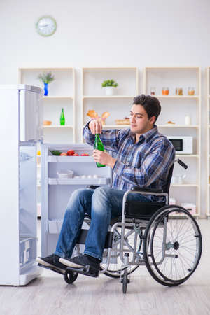 Young disabled injured man opening the fridge doorの写真素材