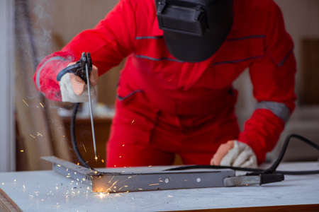 Young repairman with a welding gun electrode and a helmet weldin