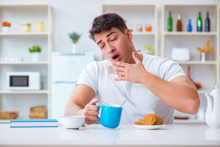 Man falling asleep during his breakfast after overtime workの写真素材