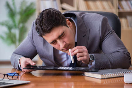 Drug addict businessman in the officeの写真素材