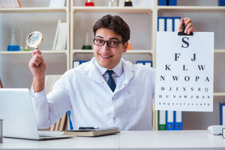 Doctor optician with letter chart conducting an eye test checkの写真素材