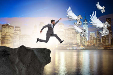 Businessman chasing angel dollars in business conceptの写真素材