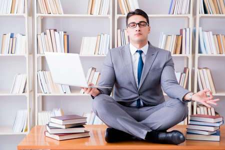 Businessman student in lotus position meditating with a laptop iの写真素材