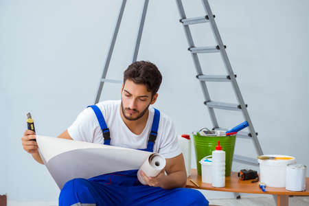 Repairman doing renovation repair in the house with paper wallpaの写真素材