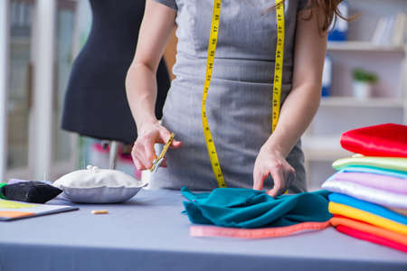 Woman tailor working on a clothing sewing stitching measuring faの写真素材