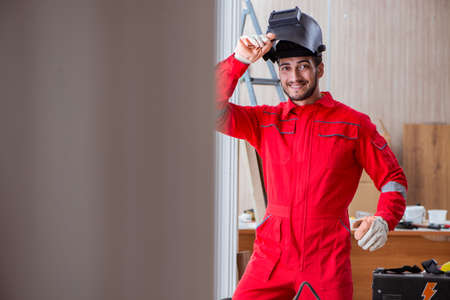 Young repairman with a welding gun electrode and a helmet weldinの写真素材