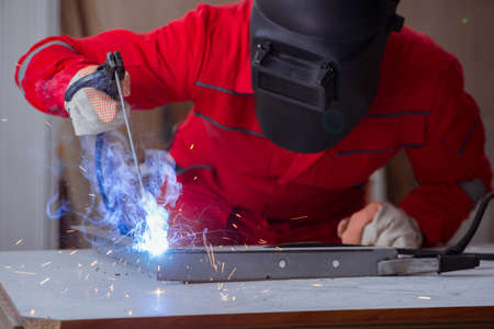 Young repairman with a welding gun electrode and a helmet weldin