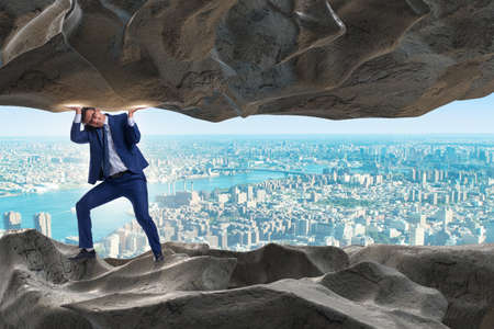 Businessman supporting stone under pressureの写真素材