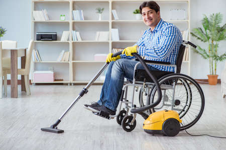 Disabled man cleaning home with vacuum cleanerの写真素材