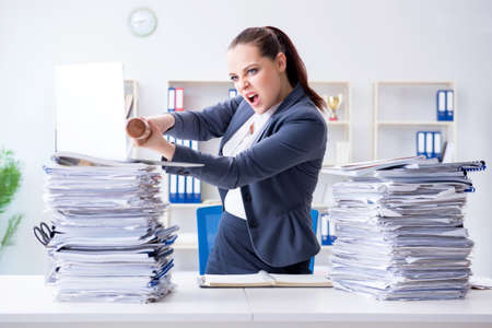 Angry businesswoman with baseball bat in officeの写真素材