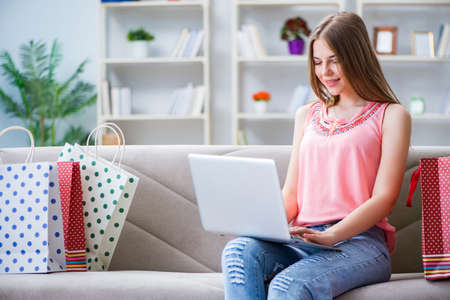 Young woman with shopping bags indoors home on sofaの写真素材
