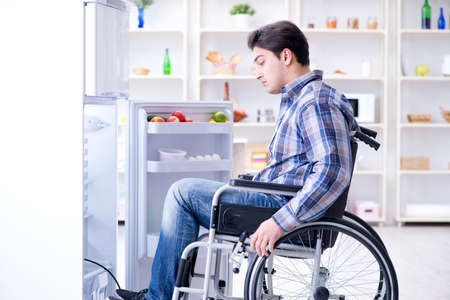 Young disabled injured man opening the fridge door