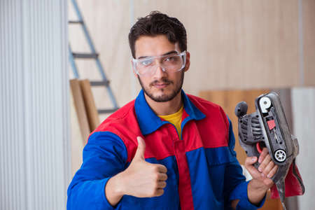 Young repairman working with a power saw sawingの写真素材