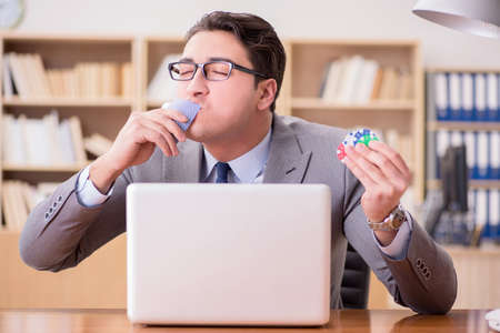 Businessman gambling playing cards at workの写真素材