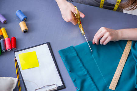 Woman tailor working on a clothing sewing stitching measuring fabric