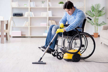 Disabled man cleaning home with vacuum cleanerの写真素材