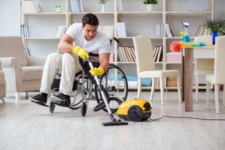 Disabled man with vacuum cleaner at homeの写真素材
