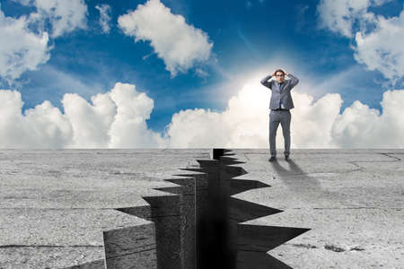 Businessman standing scared next to cliffの写真素材