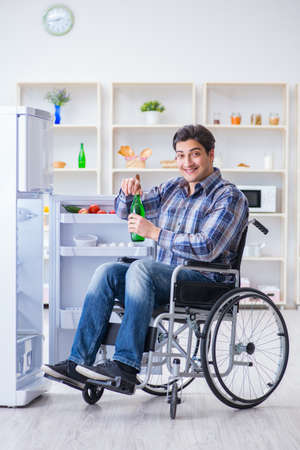 Young disabled injured man opening the fridge doorの写真素材