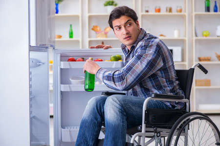 Young disabled injured man opening the fridge doorの写真素材