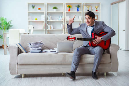 Businessman playing guitar at homeの写真素材