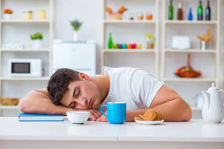 Man falling asleep during his breakfast after overtime workの写真素材