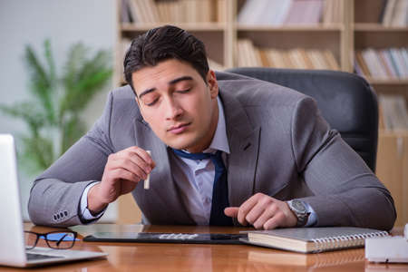Drug addict businessman in the officeの写真素材