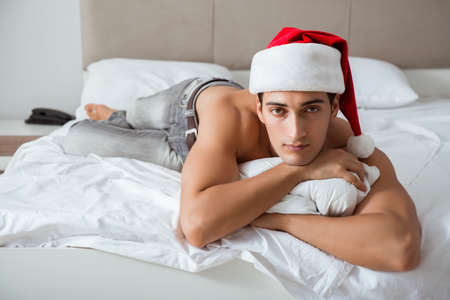Young sexy man wearing santa hat in bedの写真素材