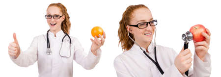 Pretty female doctor with stethoscope and orange isolated on whiの写真素材