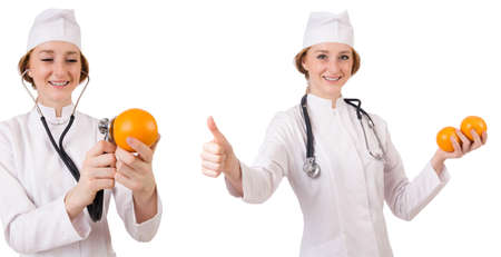 Pretty female doctor holding orange isolated on whiteの写真素材