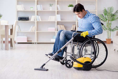 Disabled man cleaning home with vacuum cleanerの写真素材