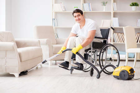 Disabled man with vacuum cleaner at homeの写真素材