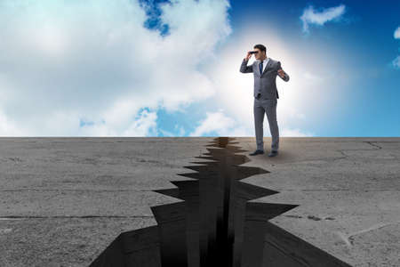 Businessman looking with binoculars at cliff edgeの写真素材