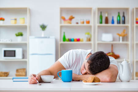 Man falling asleep during his breakfast after overtime workの写真素材