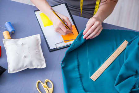 Woman tailor working on a clothing sewing stitching measuring fa