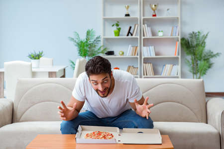 Man eating pizza having a takeaway at home relaxing restingの写真素材