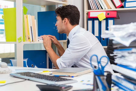 Businessman working in the office with piles of books and papers