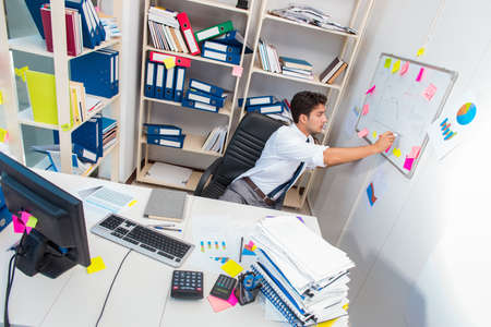 Businessman working in the office with piles of books and papers