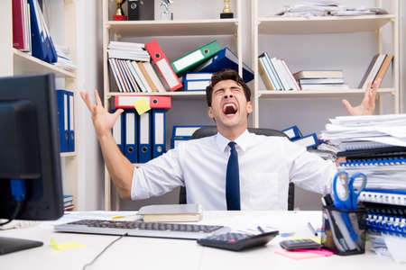 Businessman working in the office with piles of books and papers