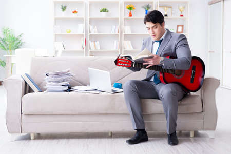 Businessman playing guitar at homeの写真素材