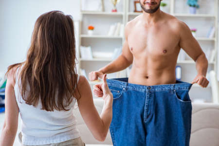 Man in oversized pants in weight loss concept with girlfriend wiの写真素材