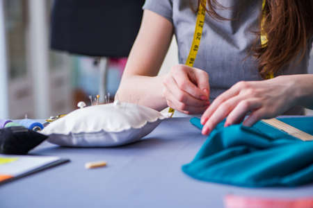 Woman tailor working on a clothing sewing stitching measuring fabricの写真素材