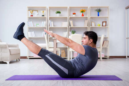 Young man exercising at home in sports and healthy lifestyle conの写真素材