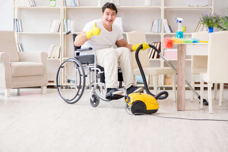 Disabled man with vacuum cleaner at homeの写真素材