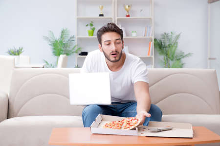 Man eating pizza having a takeaway at home relaxing restingの写真素材