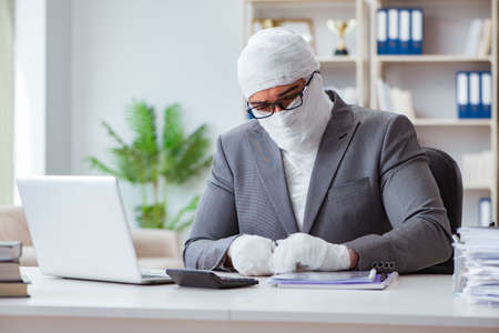 Bandaged businessman worker working in the office doing paperworの写真素材
