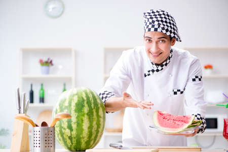 Male cook with watermelon in kitchenの写真素材