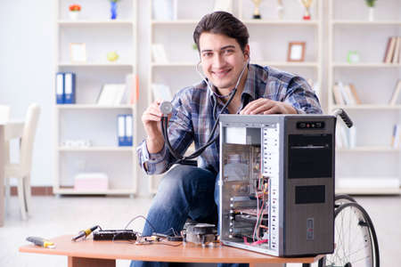 Disabled man on wheelchair repairing computerの写真素材